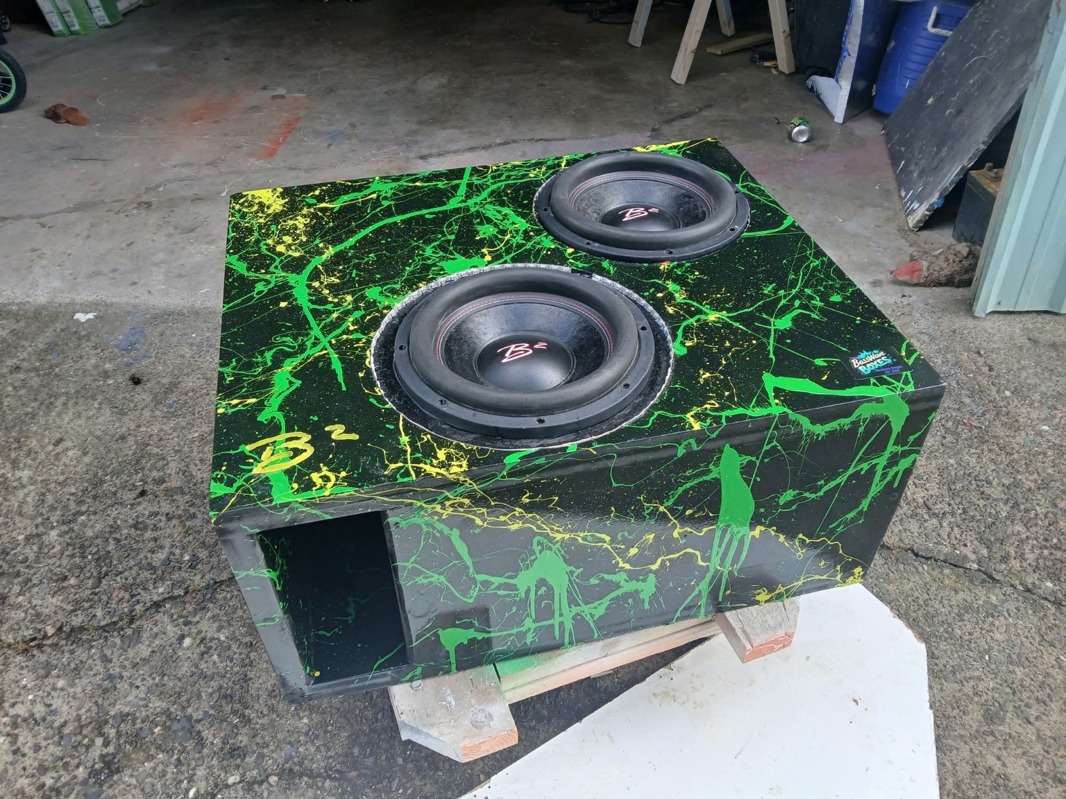 Black enclosure with green and yellow splatter, two installed B2 subwoofers and a slot port