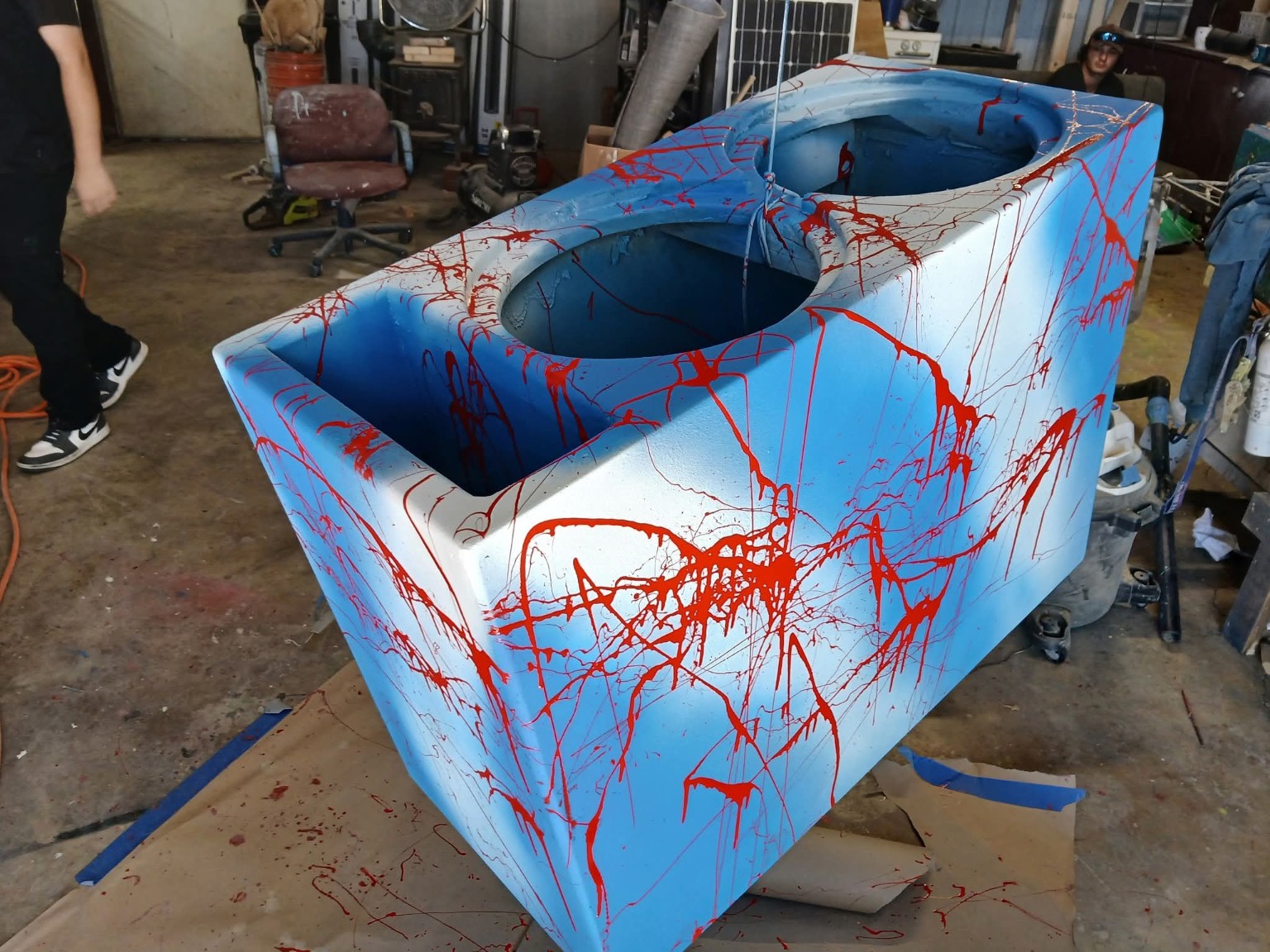 Blue and white dual-subwoofer enclosure with red splatter and rounded openings