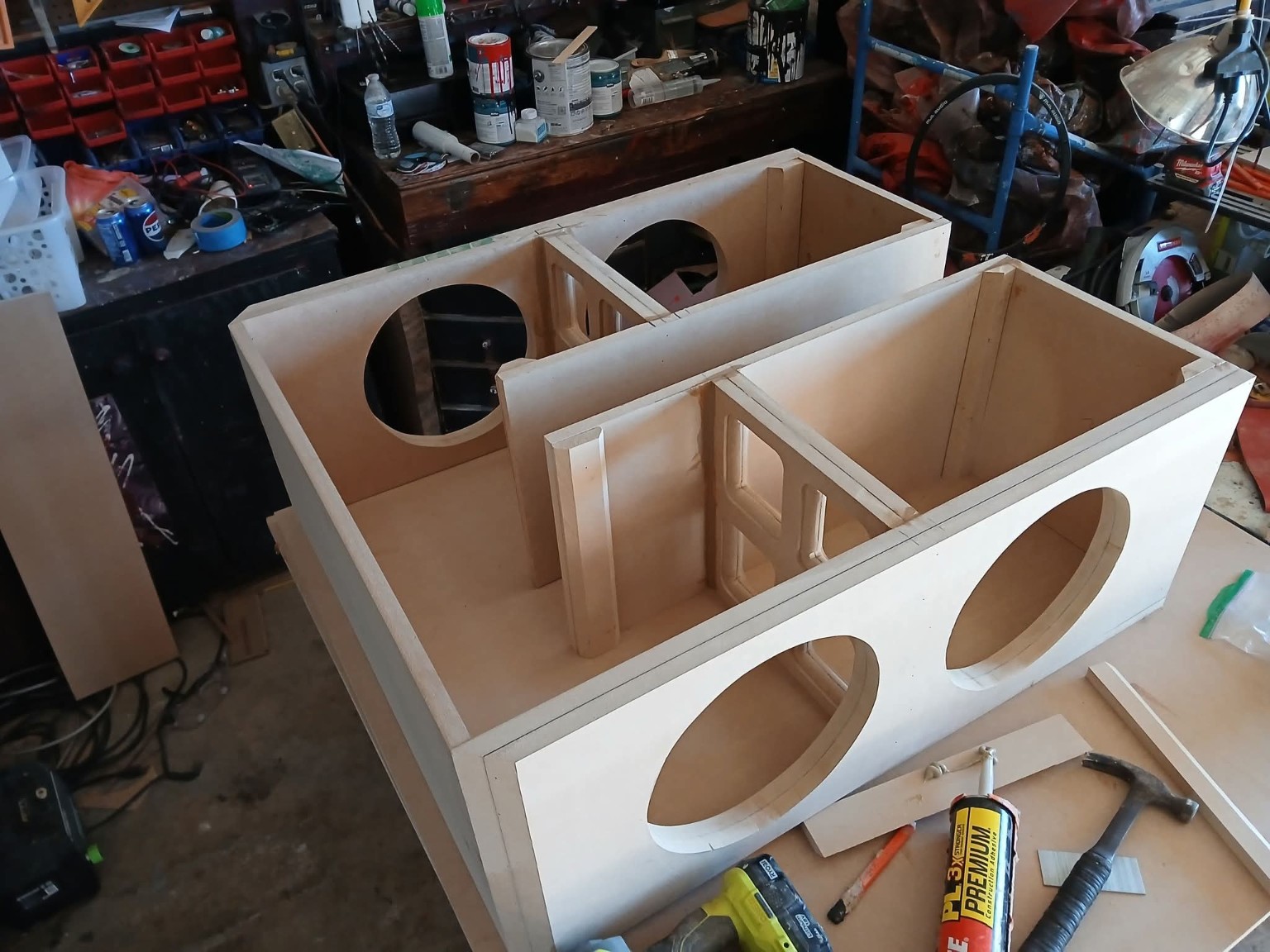 Unfinished wooden enclosure showing internal bracing, partitions and subwoofer cutouts
