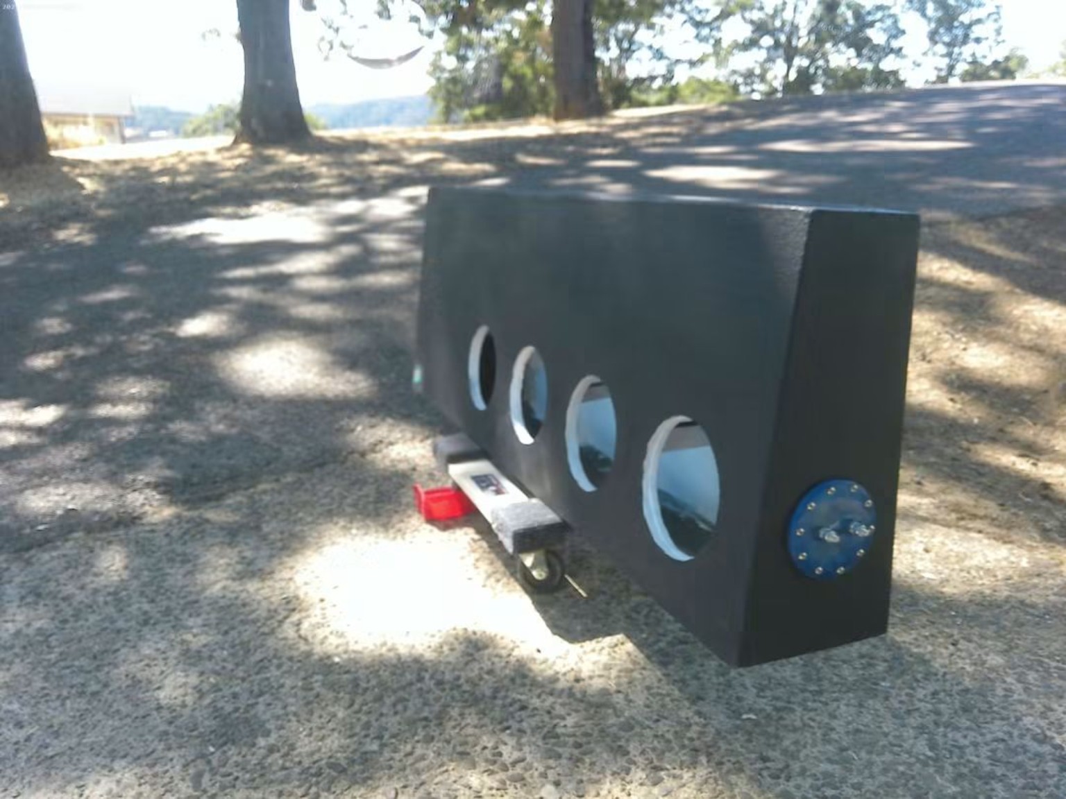 Black enclosure with four round subwoofer openings and a blue terminal plate