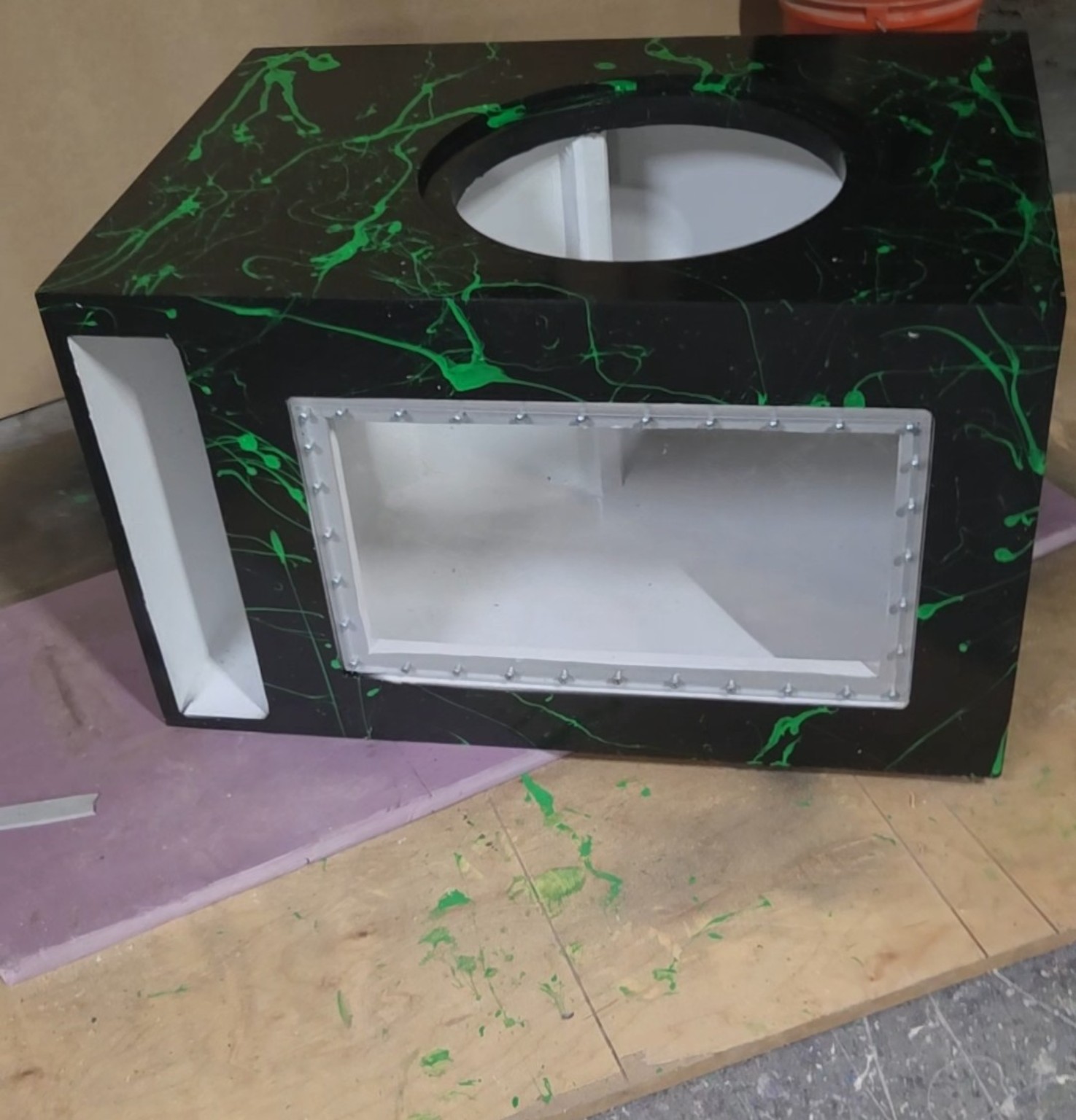 Black and green splatter enclosure with a clear front window and side port