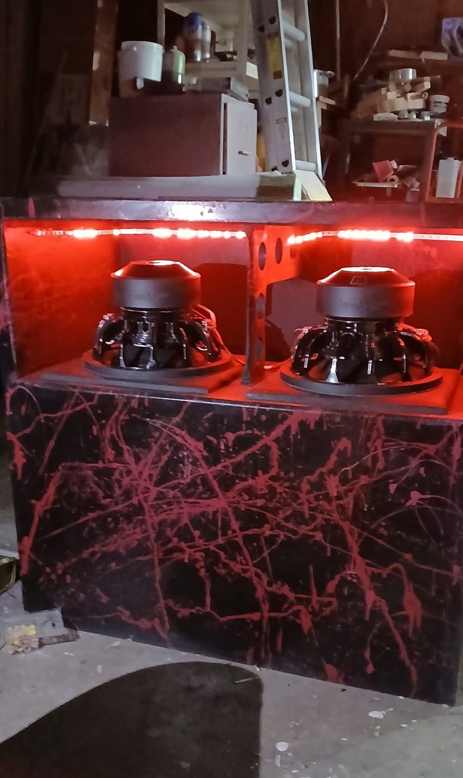 Red illuminated enclosure with two subwoofer motors and a black and red splatter finish