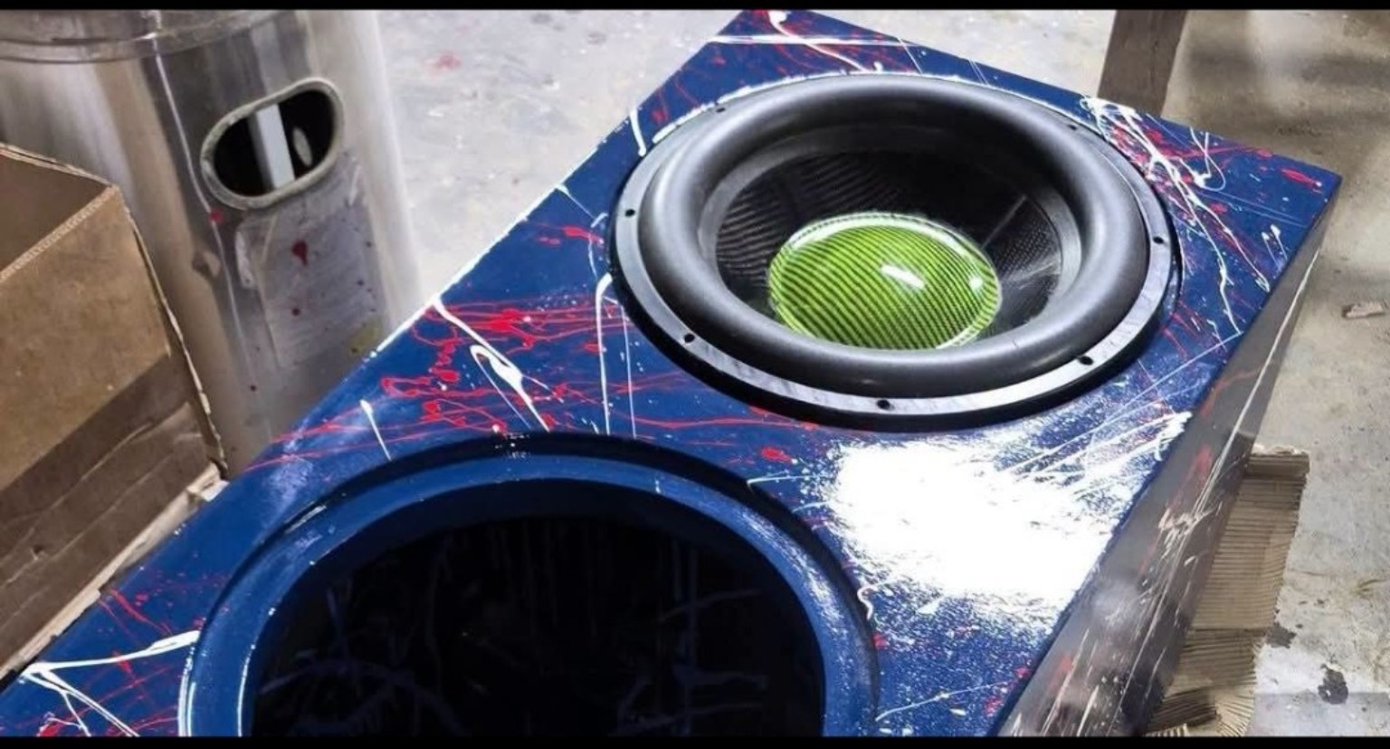 Close-up of a blue splatter enclosure with a green dust-cap subwoofer and a second opening